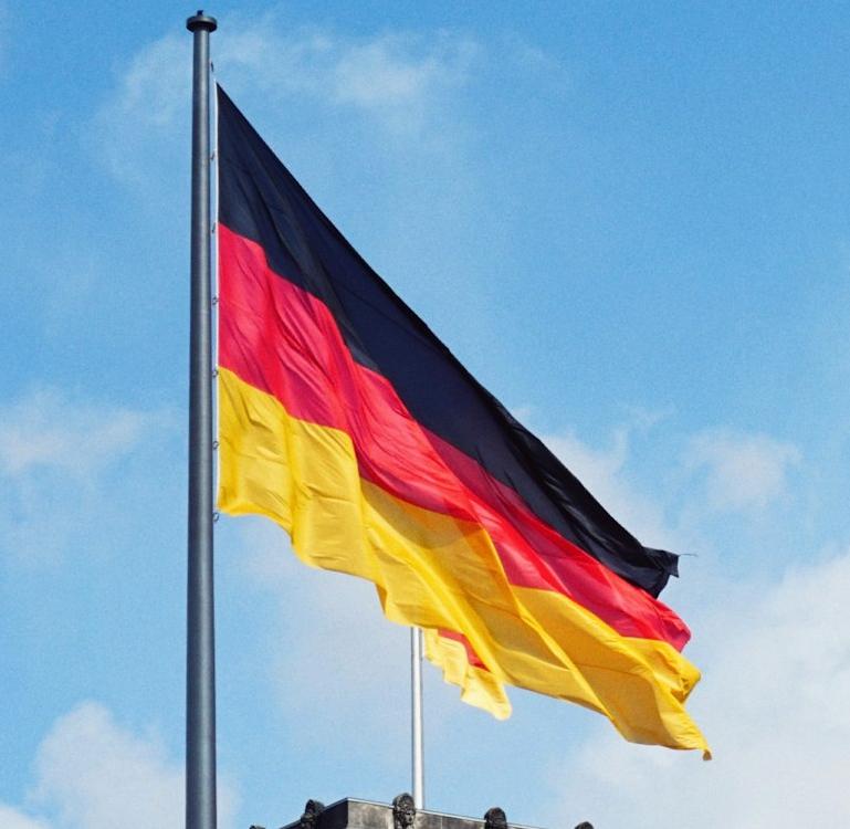white concrete building with flags on top under blue sky during daytime